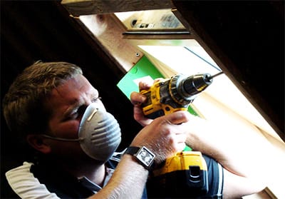 fitter working in loft with face mask