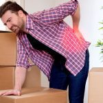 Man with back pain from lifting boxes into his loft in the wrong way